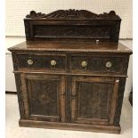 A carved oak cupboard in the 17th Century style with raised back over two drawers and two foliate