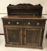 A carved oak cupboard in the 17th Century style with raised back over two drawers and two foliate