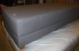 A grey fabric covered day bed on squat square tapered beech supports,