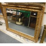 A modern swept giltwood and gesso framed wall mirror with rectangular bevel edge plate,