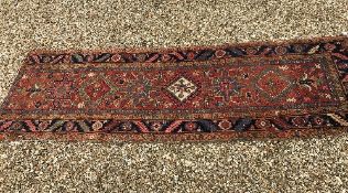 A Heriz runner, the central panel set with repeating medallions on a red ground,