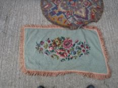 A needlework rug, the green ground set with floral spray within a tasselled edge approx.