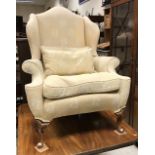 A modern upholstered wing back scroll armchair on shell carved cabriole legs to pad feet in the