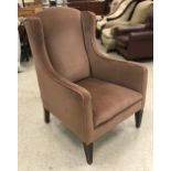 A circa 1900 mushroom upholstered wing back armchair on square tapered legs,