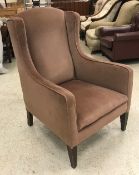 A circa 1900 mushroom upholstered wing back armchair on square tapered legs,