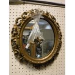 A 19th Century oval giltwood foliate carved framed wall mirror in the Florentine manner,