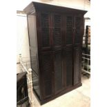 An Eastern dark lacquered cupboard with four pairs of louvre style doors, raised on a plinth base,