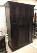 An Eastern dark lacquered cupboard with four pairs of louvre style doors, raised on a plinth base,