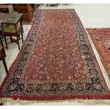 A Sarouk rug with all over scrolling floral and foliate decoration on a plum ground within a blue
