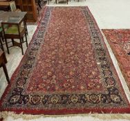 A Sarouk rug with all over scrolling floral and foliate decoration on a plum ground within a blue