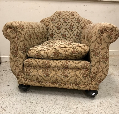 A pair of early 20th Century floral upholstered deep seated scroll armchairs on squat bun front