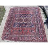 A Persian carpet, the central panel set with two medallions on a red,