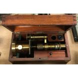 A 19th Century lacquered brass monocular microscope on a circular base, un-named, 23 cm high,
