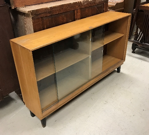 A set of three 20th Century ash sliding glazed door cabinets of plain form raised on ebonised