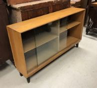 A set of three 20th Century ash sliding glazed door cabinets of plain form raised on ebonised