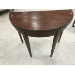 A 19th Century mahogany fold-over card table of demi-lune form, raised on square tapered legs,