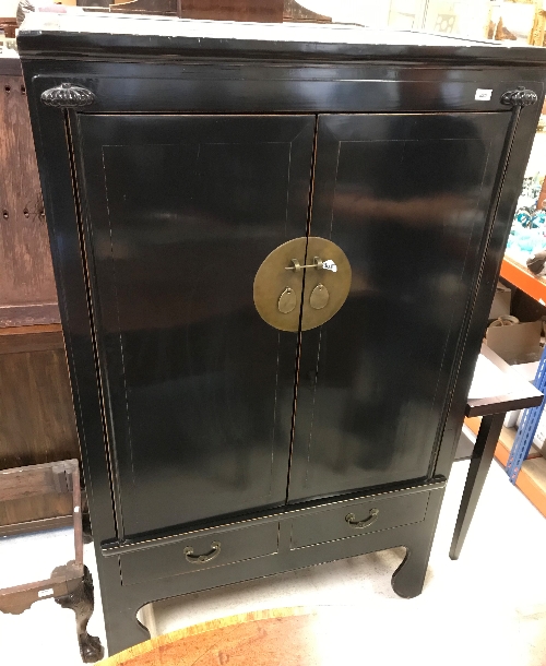 A Chinese black lacquered wedding cabinet, the two doors enclosing two shelves,