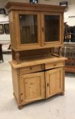 A Continental pine buffet, the glazed two door upper section enclosing two shelves,