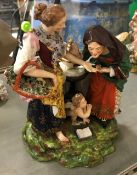 A Derby porcelain figure group as a young woman with basket of flowers and old woman by a small tea