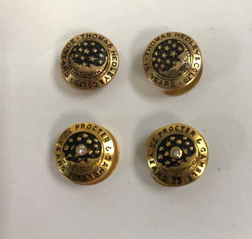 A collection of four 9 carat gold and enamelled Long Service buttons inscribed "Proctor & Gamble",