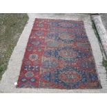 An old Sumak rug section with repeating medallions on a blue and red ground with stylized flower