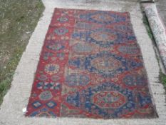 An old Sumak rug section with repeating medallions on a blue and red ground with stylized flower