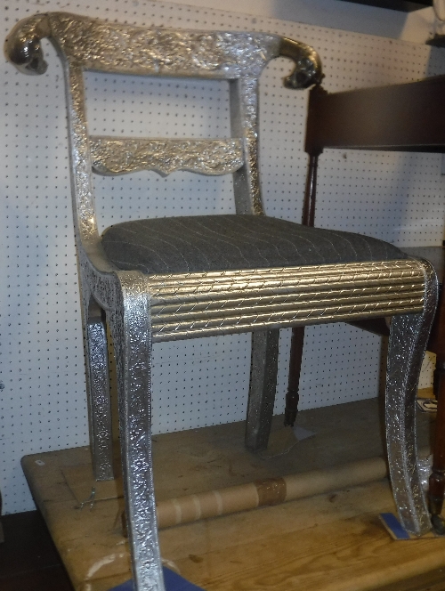 A pair of Continental embossed silver coloured metal covered bar back chairs with ram's head