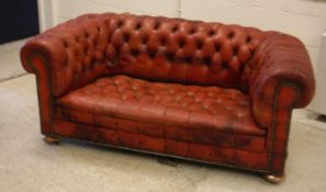 A circa 1900 buttoned red leather upholstered chesterfield scroll arm sofa on squat bun feet 163 cm