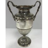 A George V twin-handled trophy cup with embossed floral decoration and raised on an acanthus leaf