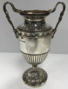 A George V twin-handled trophy cup with embossed floral decoration and raised on an acanthus leaf