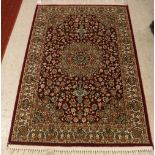 A modern Persian Kashan rug with centre medallion on a red ground within a cream ground border,