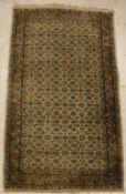 A Persian rug, the central panel set with all-over floral decoration on a cream ground,