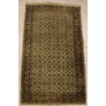 A Persian rug, the central panel set with all-over floral decoration on a cream ground,