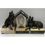 A 1930s marble and onyx cased clock garniture as a dog kennel flanked by two hounds, one seated,