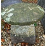 A natural stone staddle stone with circular top on a tapered base,