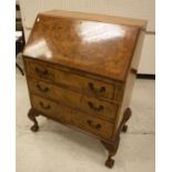 A mid 20th Century walnut bureau with sloping fall enclosing a basic fitted interior over three