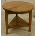 A pine cricket table, the circular plank top on three splayed supports united by an undertier,