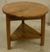 A pine cricket table, the circular plank top on three splayed supports united by an undertier,
