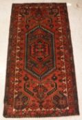 A modern Persian rug, the central panel set with lozenge shaped medallion on a red ground,