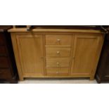 A modern light oak sideboard with four central drawers flanked by two cupboard doors,