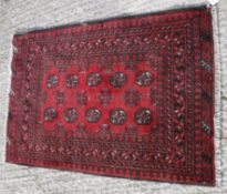 A Turkamen rug, the central panel set with repeating elephant foot style medallions on a red ground,