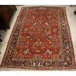 A Heriz carpet, the central panel set with all-over stylised foliate decoration on a red ground,