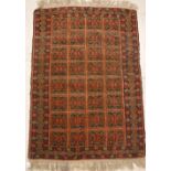 A Turkamen rug, the central panel set with repeating tiled decoration on a red ground,