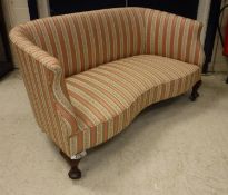 An early 20th Century upholstered scroll arm salon sofa with shaped front rail raised on squat