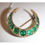 A late Victorian green garnet set 9 carat gold mounted crescent brooch with diamond chip accents,