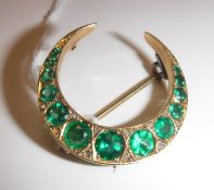 A late Victorian green garnet set 9 carat gold mounted crescent brooch with diamond chip accents,