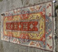 A Turkish rug, the central panel set with geometric design on a mustard and terracotta ground,