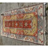 A Turkish rug, the central panel set with geometric design on a mustard and terracotta ground,