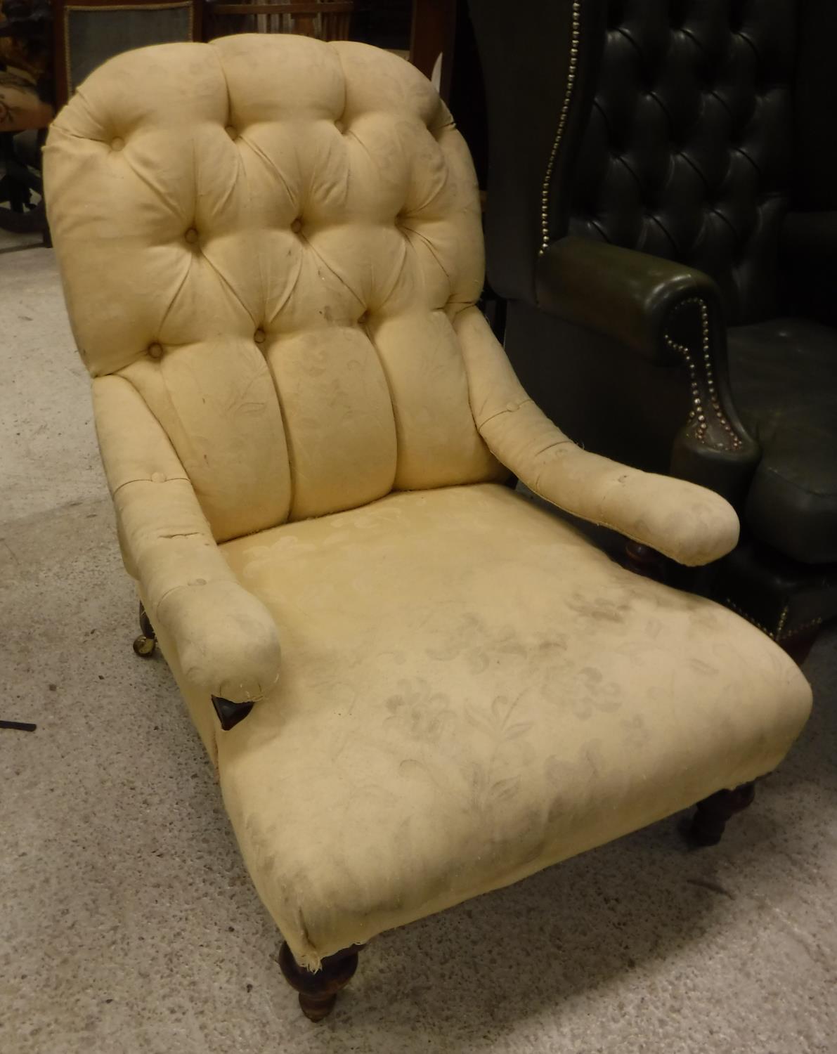 A Victorian buttoned upholstered low slung open arm salon chair on turned front legs to castors,