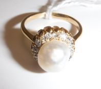 A gold-mounted (un-marked) pearl and diamond dress ring, the central pearl (approx size 17),